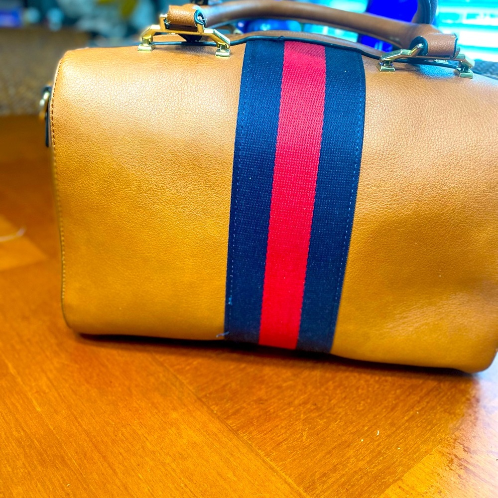 No name tan cute duffle style purse. With black and red stripe.